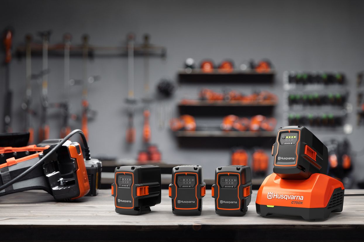 Husqvarna BLi-X Akkus und Ladegerät auf einer Werkbank