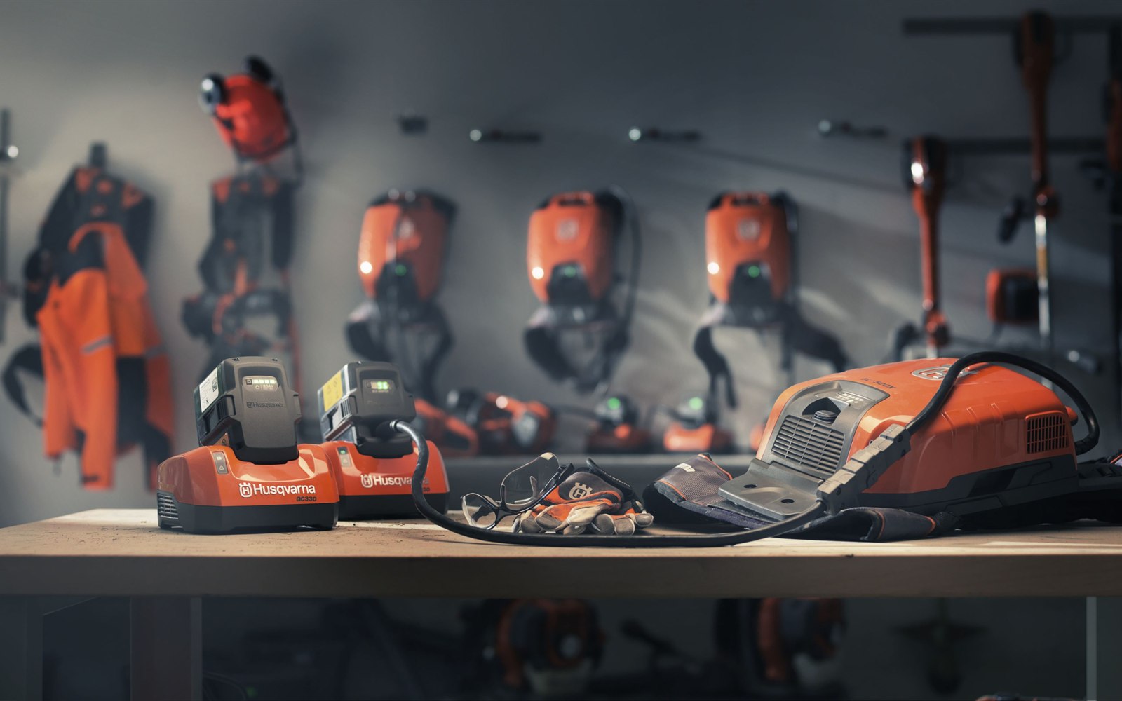 Husqvarna Akku-Systeme und Schutzkleidung auf einer Werkbank