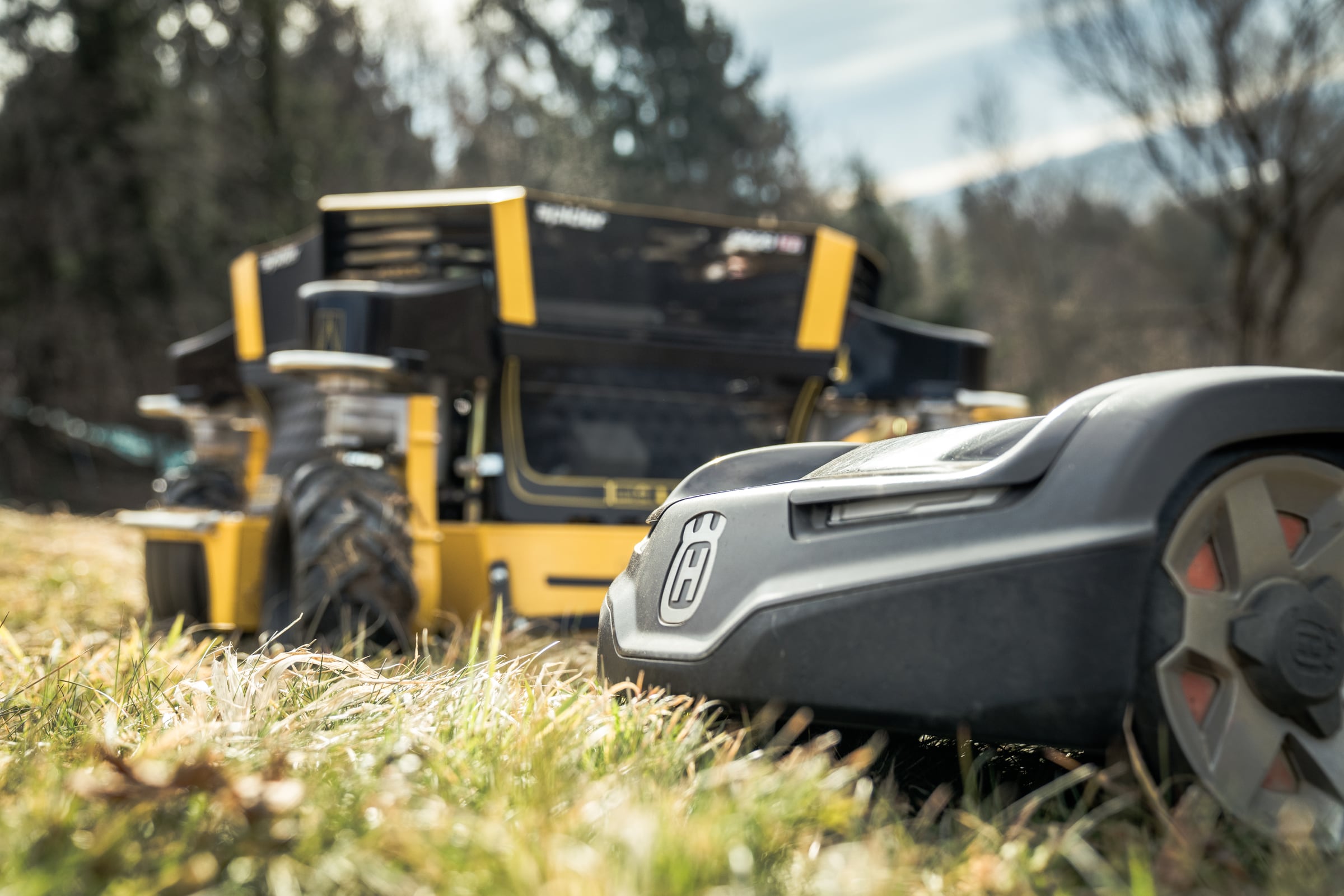 Rasentraktor und Mähroboter auf einer Rasenfläche